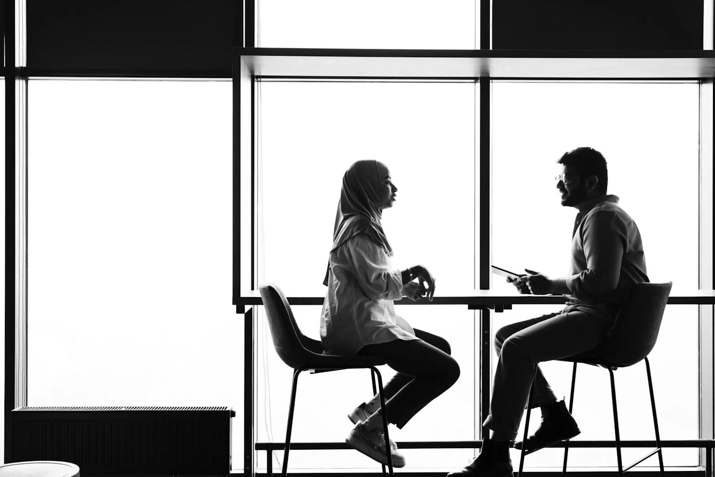 A man and a women sitting at a tall table discussing the difference between reskilling and upskilling.